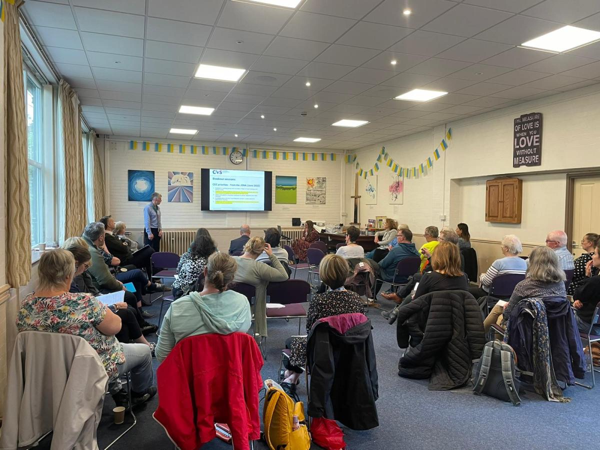 Food Alliance meeting with Graham Brown presenting at the front of a large room with people sitting and listening