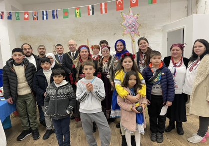 A group of refugees, including men, women and children facing the camera with Cheshire East council members